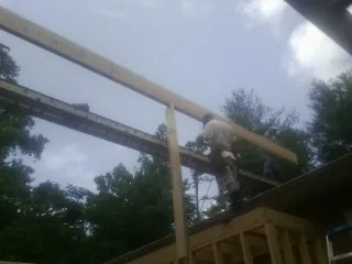 Carpenter setting a ridge beam over a new addition frame — Ice Dam Removal by Roofing Brothers in Means