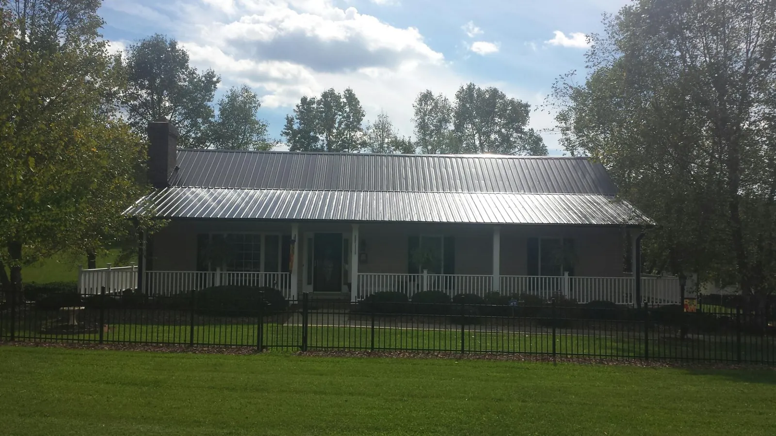 Gray metal roof on a brick ranch with a full width front porch — Gutter Guard Installation work by our crew in Means