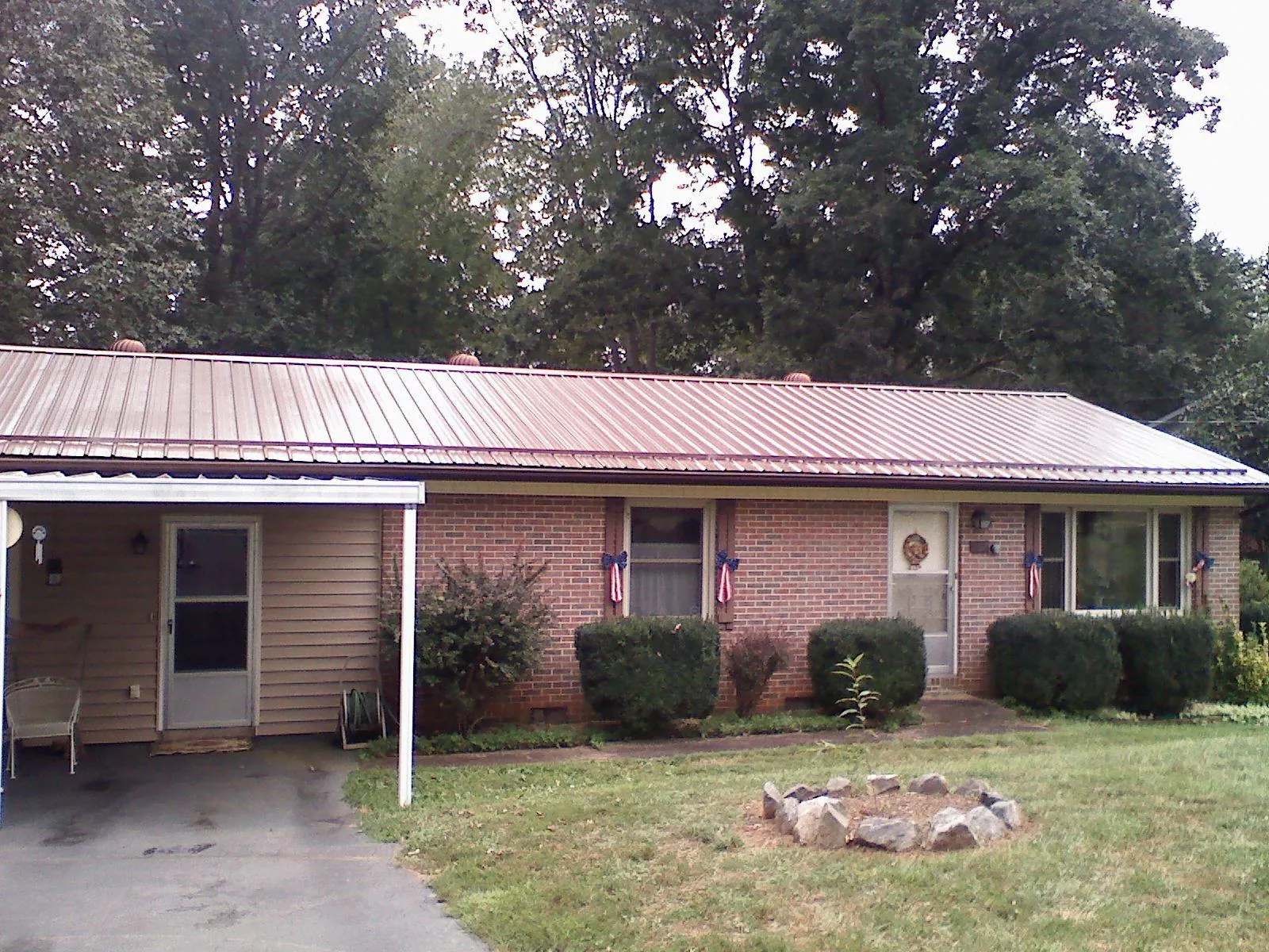 Bronze metal roof and carport on a brick ranch home — Roof Repair work by our crew in Means